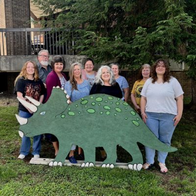 Library staff members posting for photo in front of triceratops display